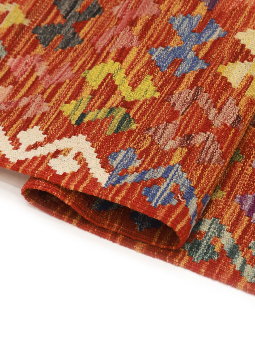A hand-woven Afghan kelim rug featuring a vibrant red field with intricate geometric patterns.