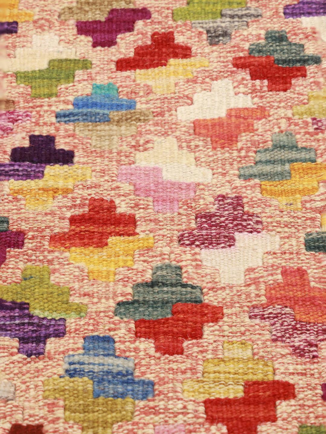 A large, one-of-a-kind Afghan Kelim rug with a vibrant, multicolored geometric pattern.