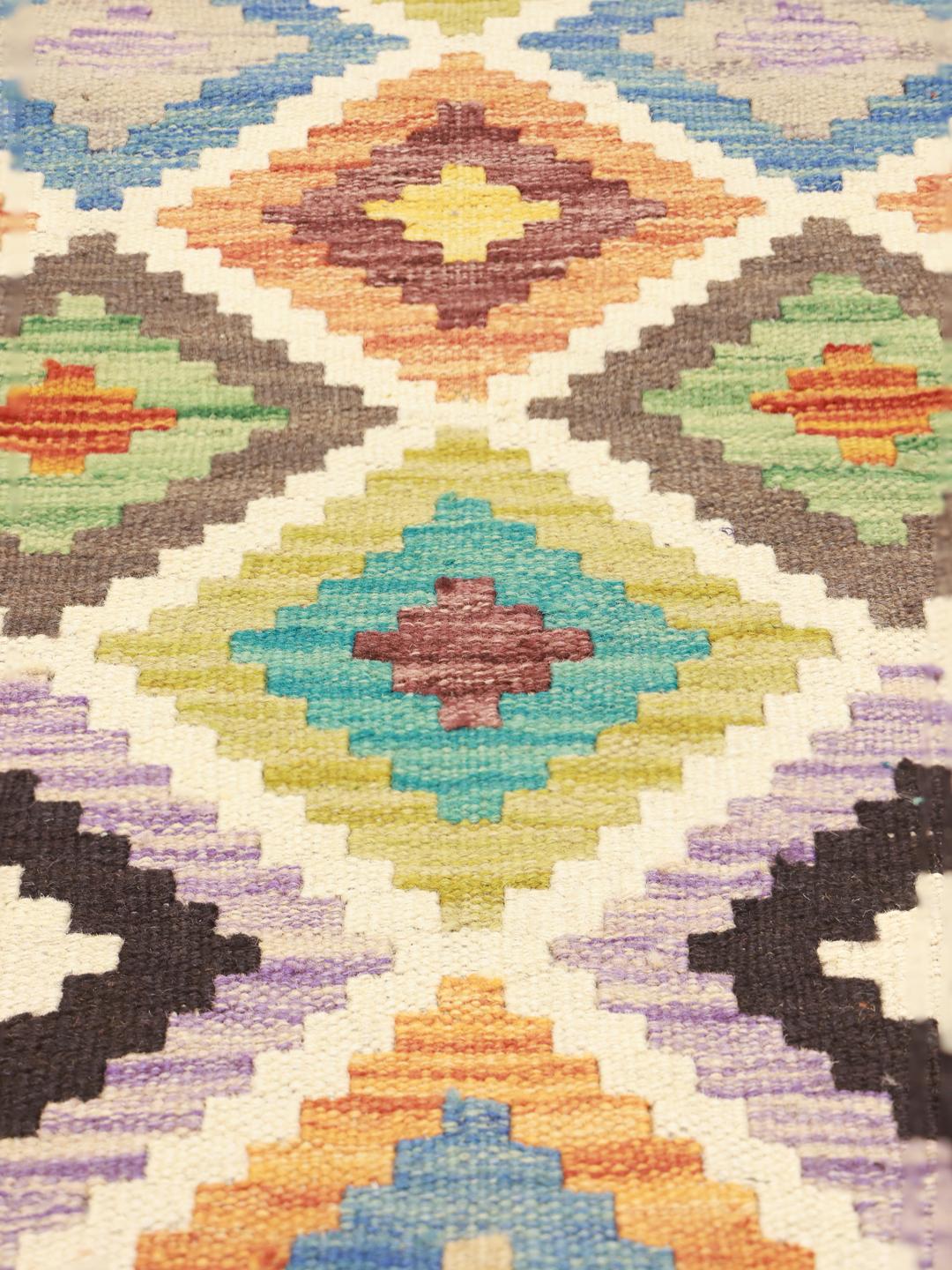 Een rechthoekig Afghan Kelim-tapijt met een levendig geometrisch ruitpatroon in veelkleurige wol.