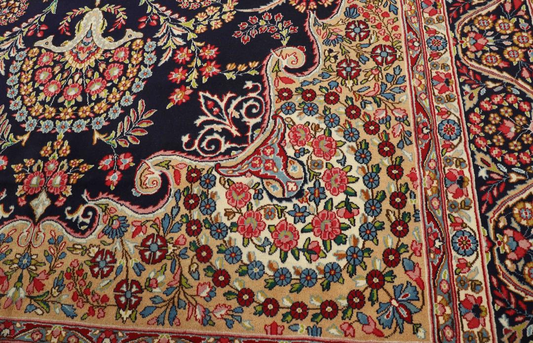 Een groot, handgeknoopt Kerman-tapijt uit het Midden-Oosten met een donkerblauw veld en een veelkleurig bloemenmedaillon.