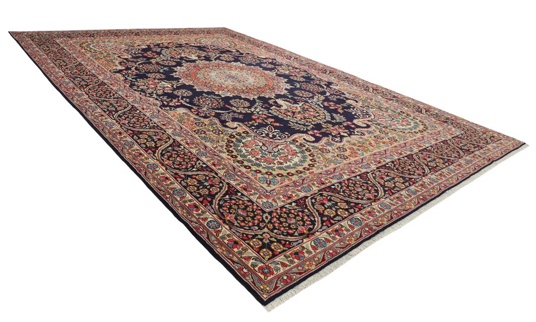 Een groot, handgeknoopt Kerman-tapijt uit het Midden-Oosten met een donkerblauw veld en een veelkleurig bloemenmedaillon.