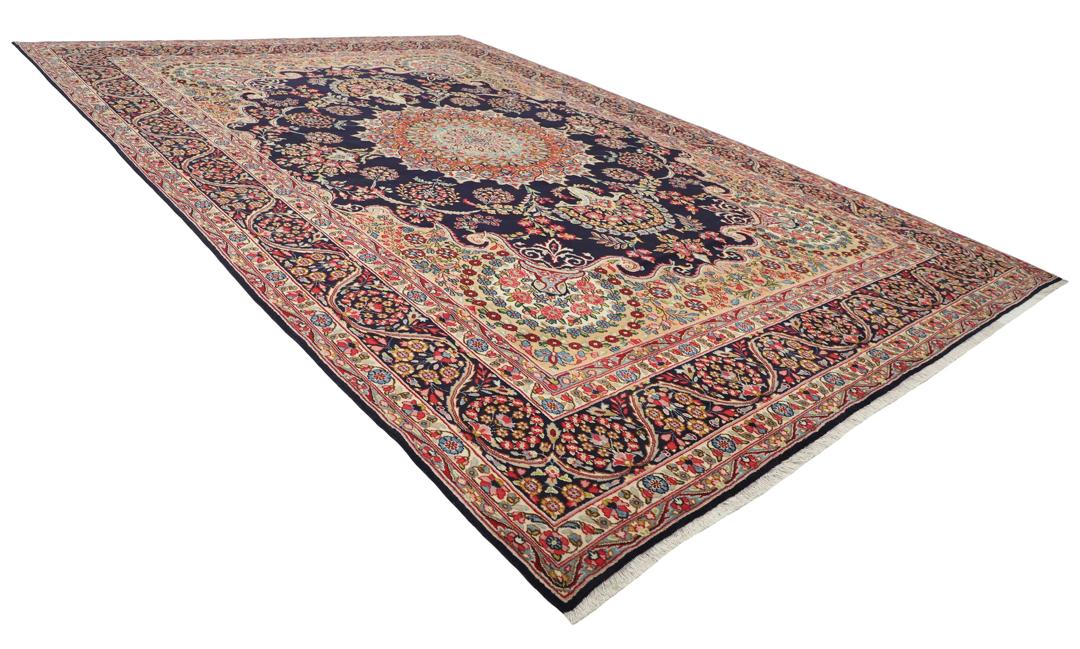 Een groot, handgeknoopt Kerman-tapijt uit het Midden-Oosten met een donkerblauw veld en een veelkleurig bloemenmedaillon.