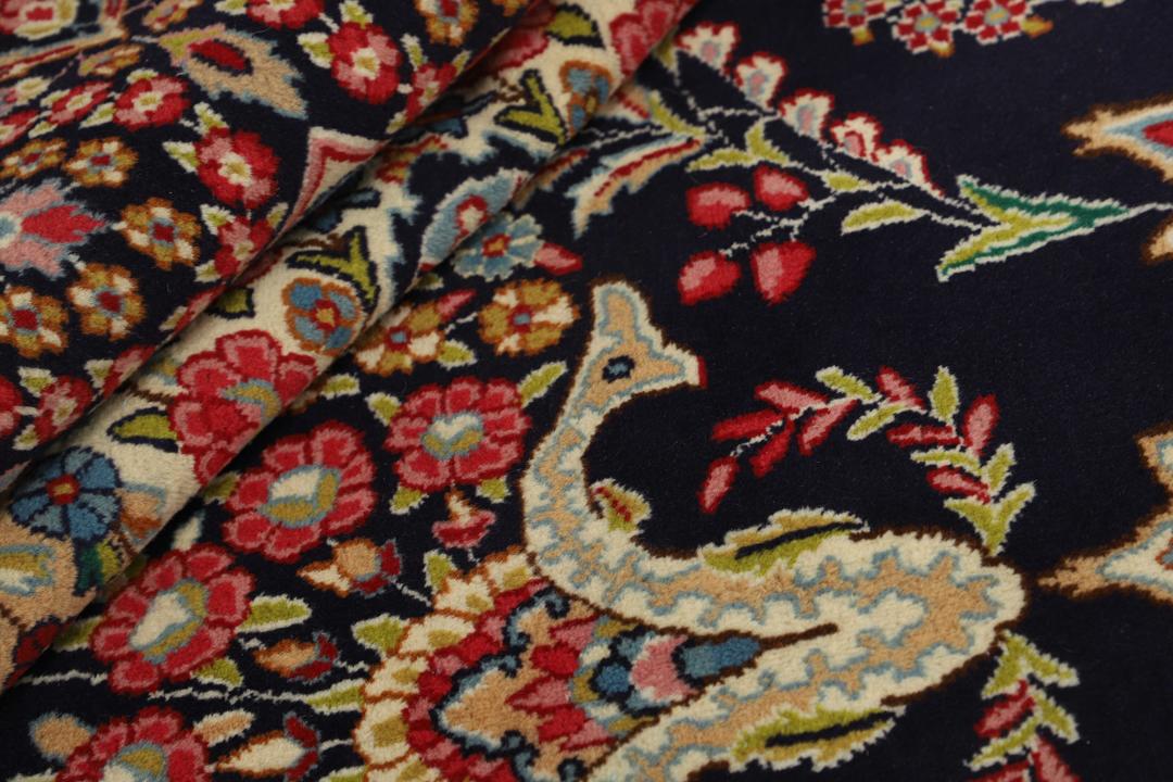 Een groot, handgeknoopt Kerman-tapijt uit het Midden-Oosten met een donkerblauw veld en een veelkleurig bloemenmedaillon.