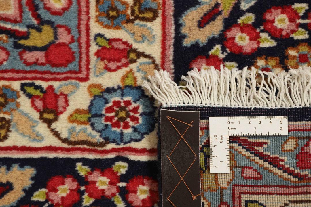 Een groot, handgeknoopt Kerman-tapijt uit het Midden-Oosten met een donkerblauw veld en een veelkleurig bloemenmedaillon.