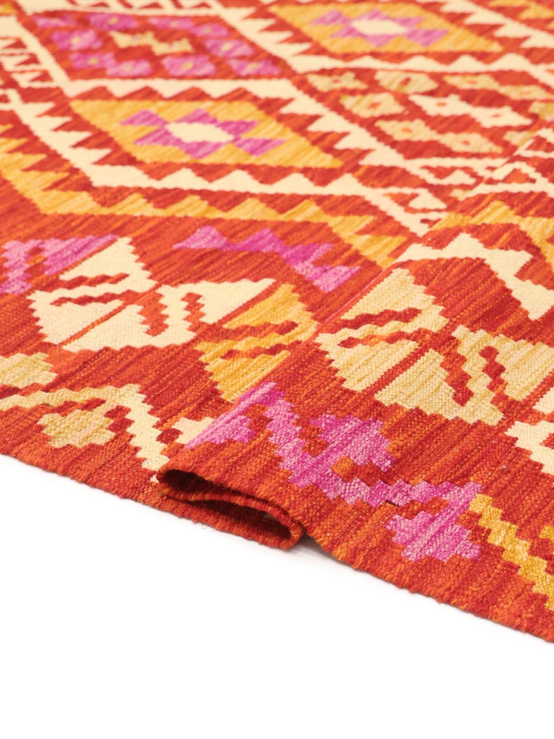 A hand-woven, one-of-a-kind Afghan Kelim rug featuring a vibrant geometric pattern in red, orange, and pink tones.