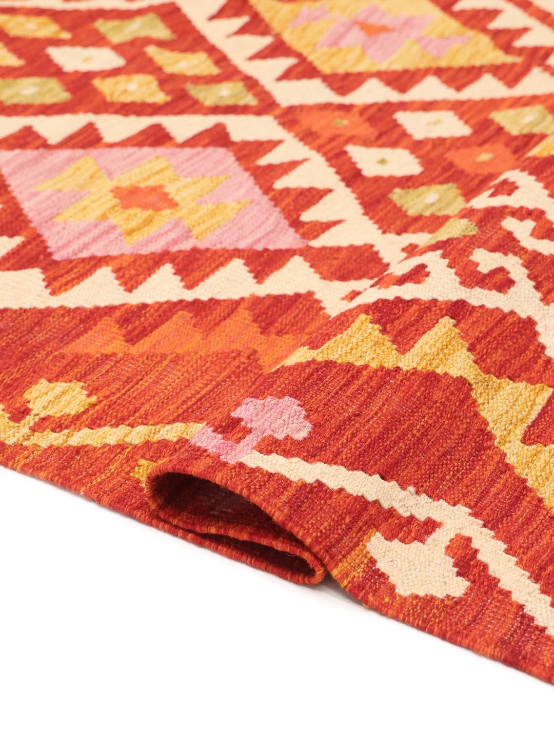 Hand-woven Afghan Kelim rug with geometric patterns in red, orange, and pink tones.