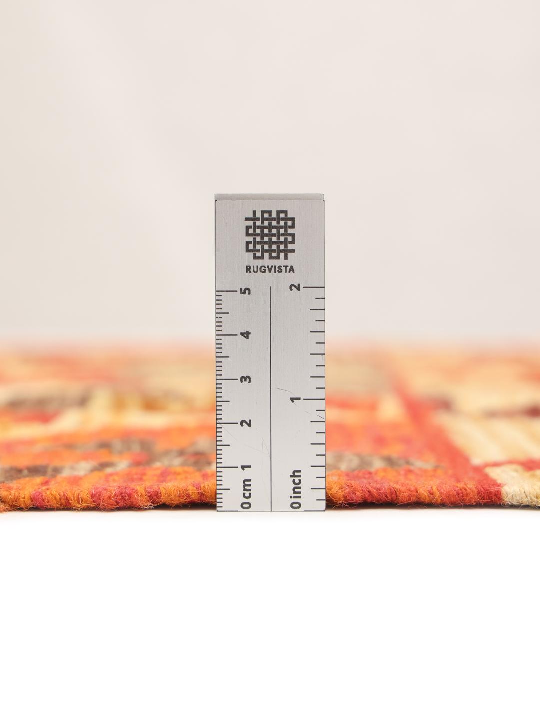 A hand-woven Afghan Kelim rug featuring geometric patterns in red, orange, and beige.