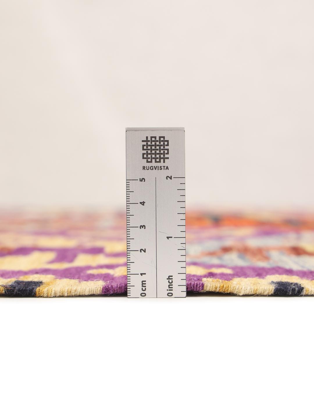 Et håndvævet Kelim-tæppe fra Afghanistan med en lilla bund og geometriske motiver.