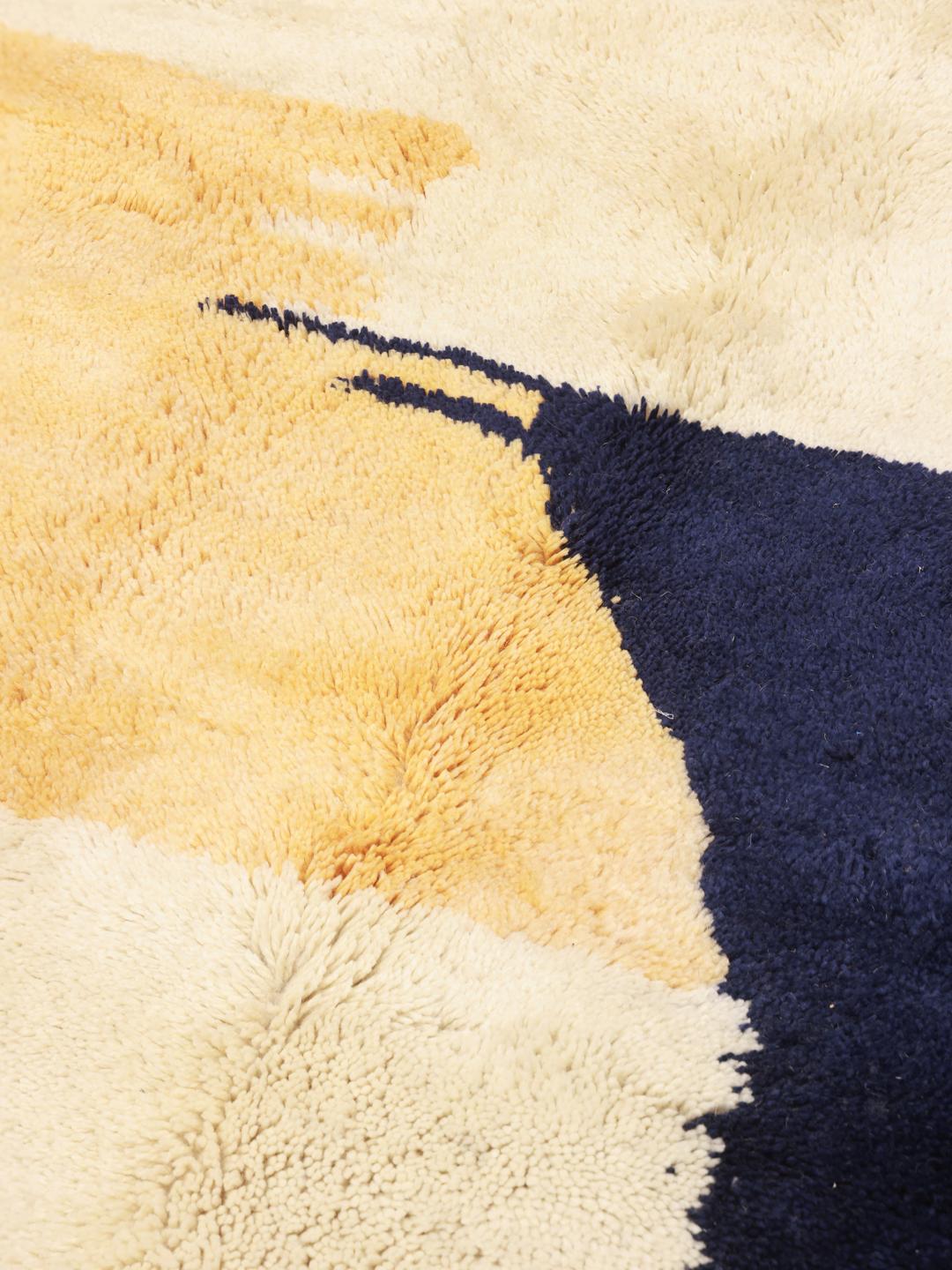 Handgeknoopt Marokkaans Berber tapijt met abstracte blauwe en gele motieven op een beige achtergrond.