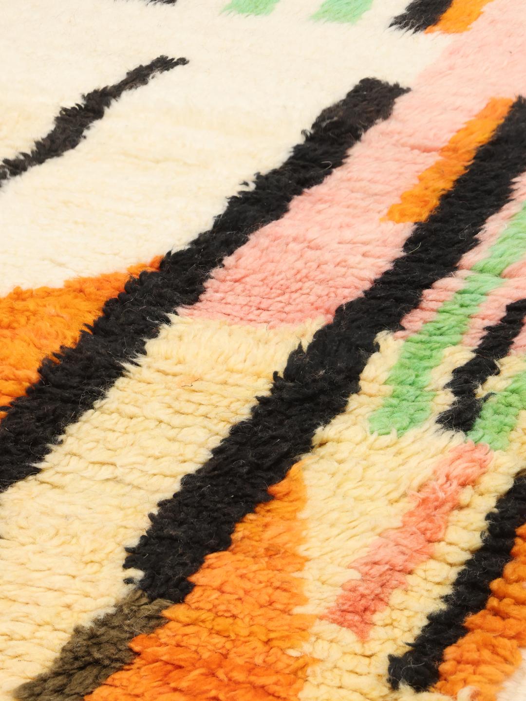 Een levendig, handgeknoopt Marokkaans Berber tapijt met abstracte motieven en felle kleuren.