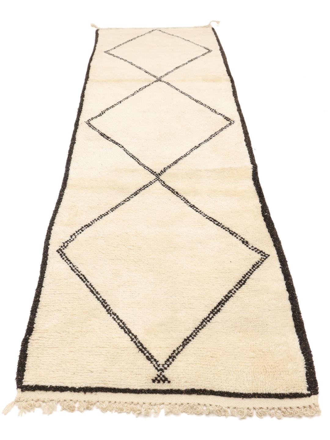 Håndknyttet marokkansk berberløber med sort diamantmønster på en beige uldbaggrund.