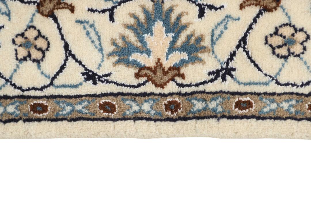 Handmade Nain rug from the Middle East with a beige field and blue floral motifs