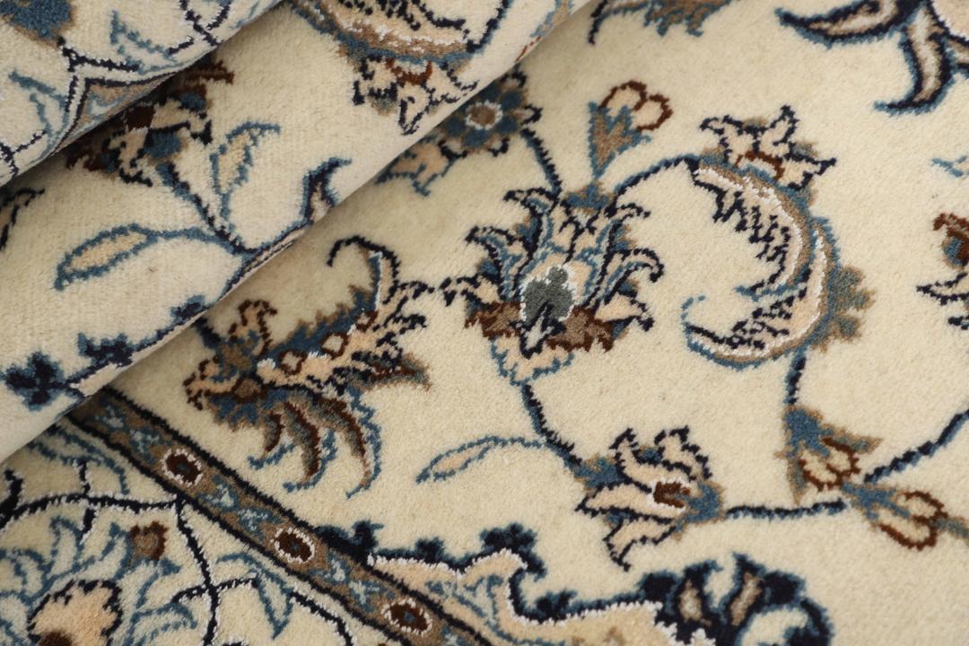 Handmade Nain rug from the Middle East with a beige field and blue floral motifs