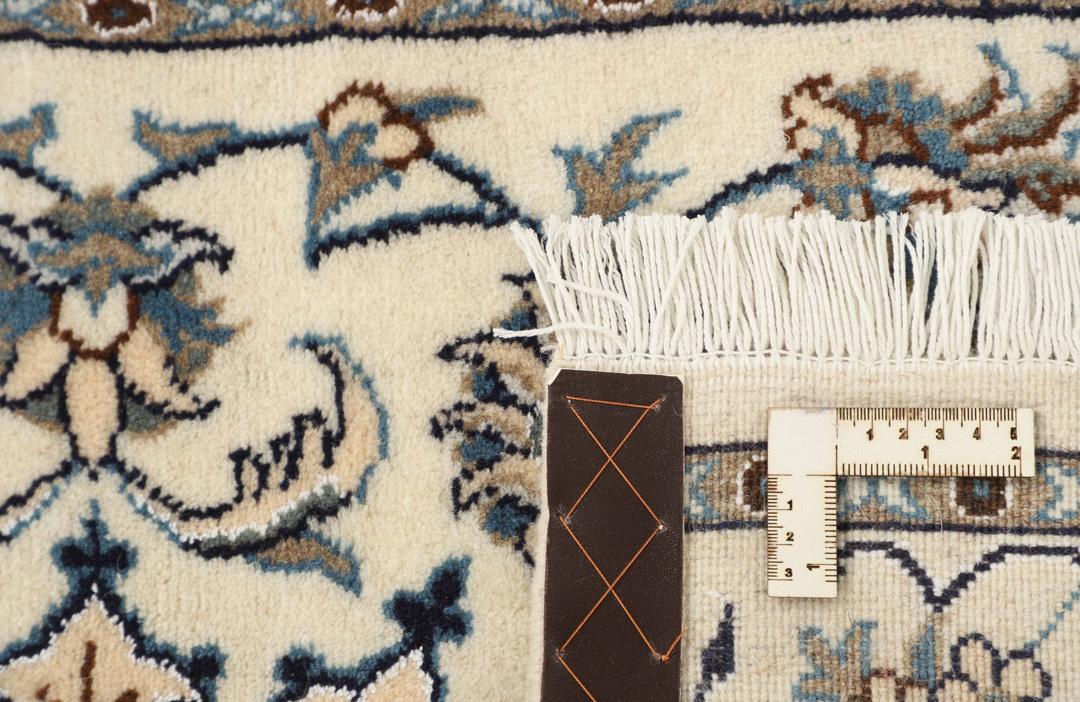 Handmade Nain rug from the Middle East with a beige field and blue floral motifs