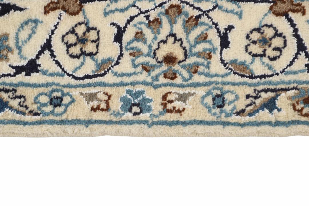 A rectangular Nain rug from the Middle East with a beige field and blue floral patterns.