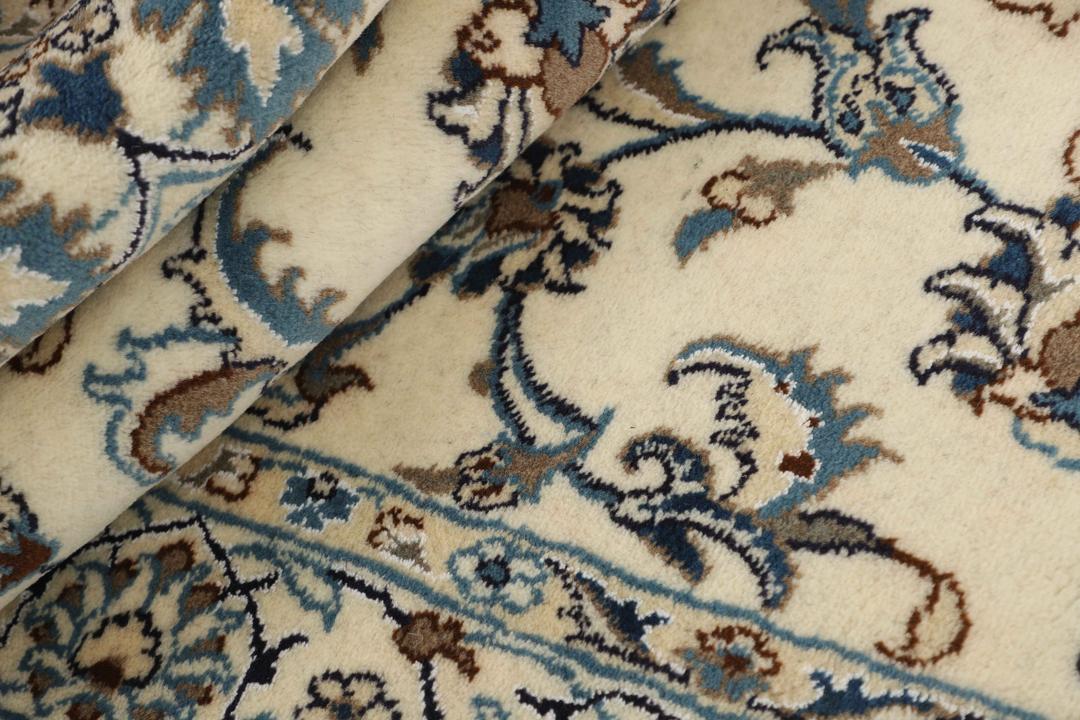 A rectangular Nain rug from the Middle East with a beige field and blue floral patterns.