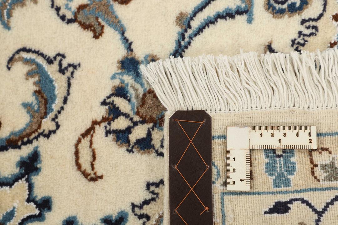 A rectangular Nain rug from the Middle East with a beige field and blue floral patterns.