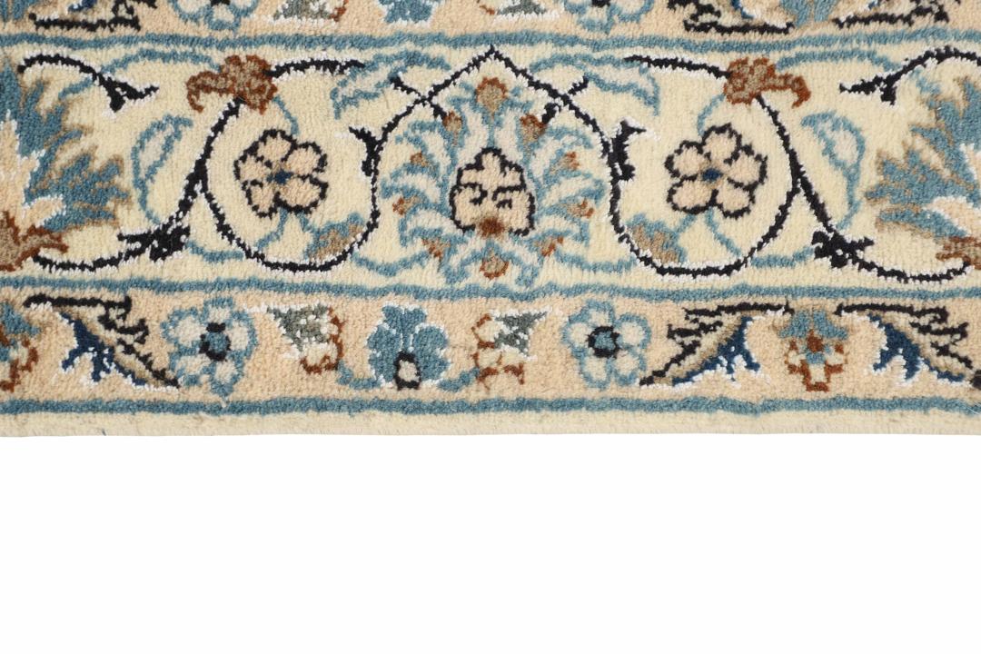 A rectangular handmade Nain rug from the Middle East featuring a blue field with floral patterns.