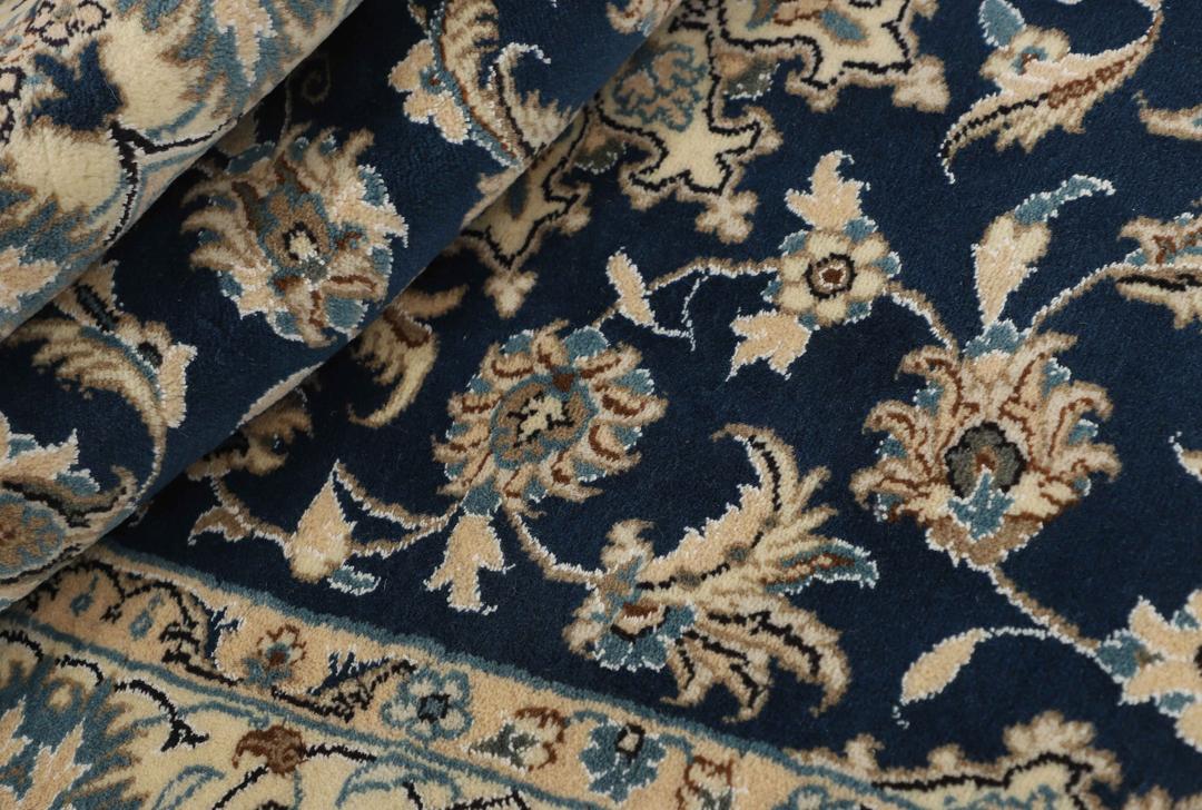 A rectangular handmade Nain rug from the Middle East featuring a blue field with floral patterns.