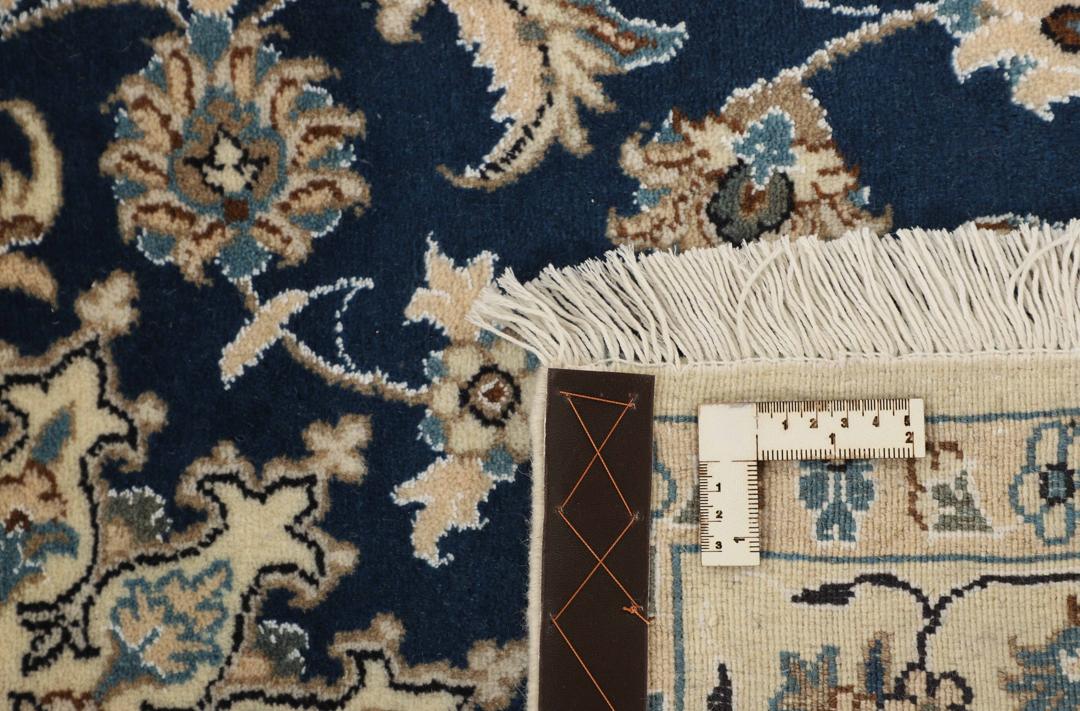 A rectangular handmade Nain rug from the Middle East featuring a blue field with floral patterns.