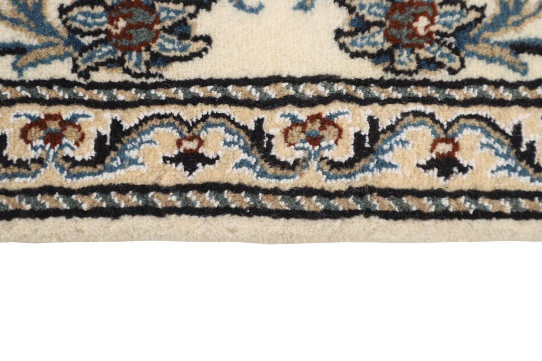 Hand-knotted Nain runner with a beige field and floral motifs in blue and earth tones