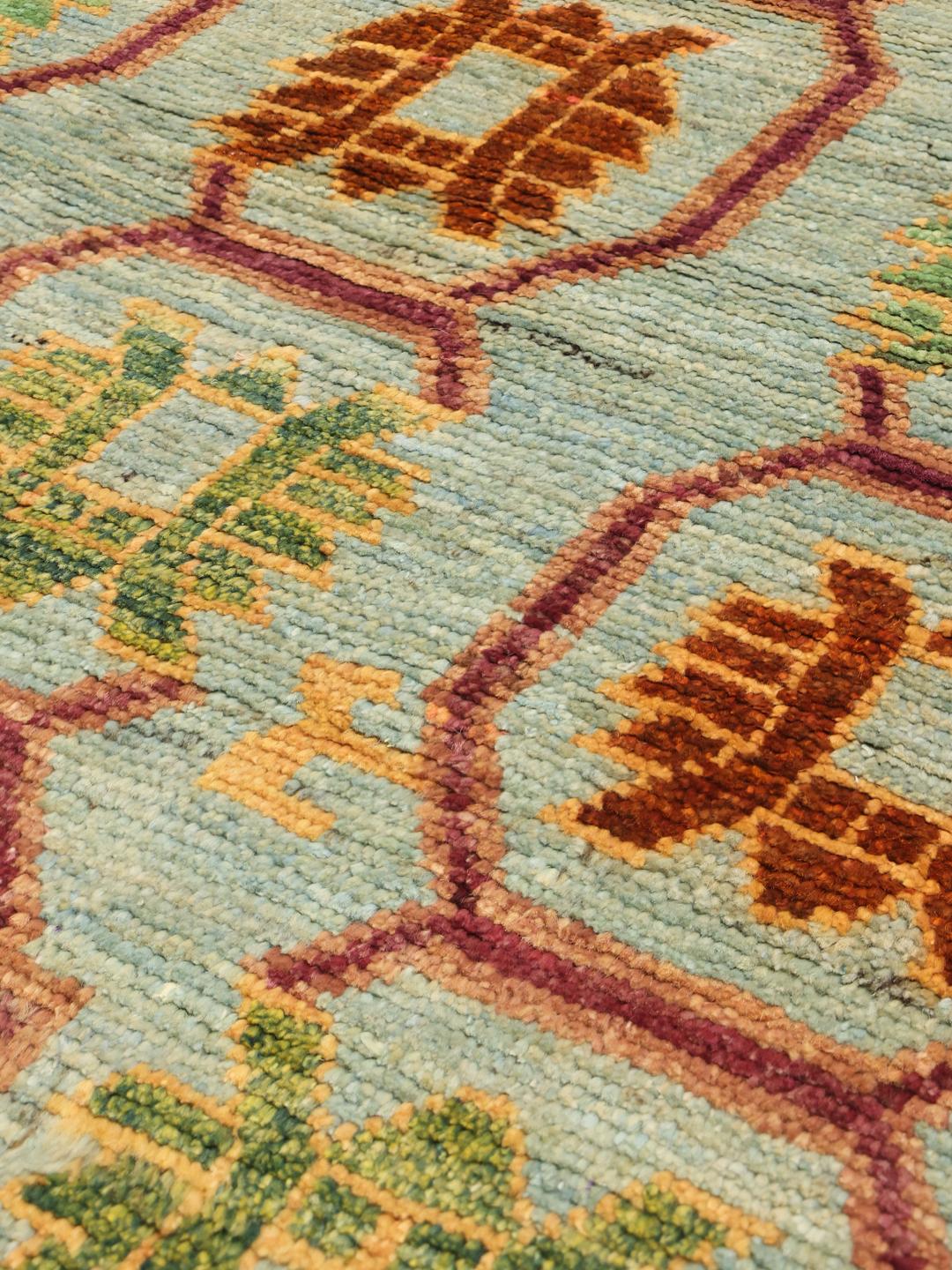 A hand-knotted Afghan runner with a vibrant geometric pattern on a light blue background.