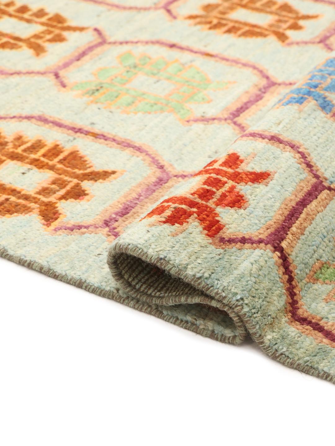 A hand-knotted Afghan runner with a vibrant geometric pattern on a light blue background.