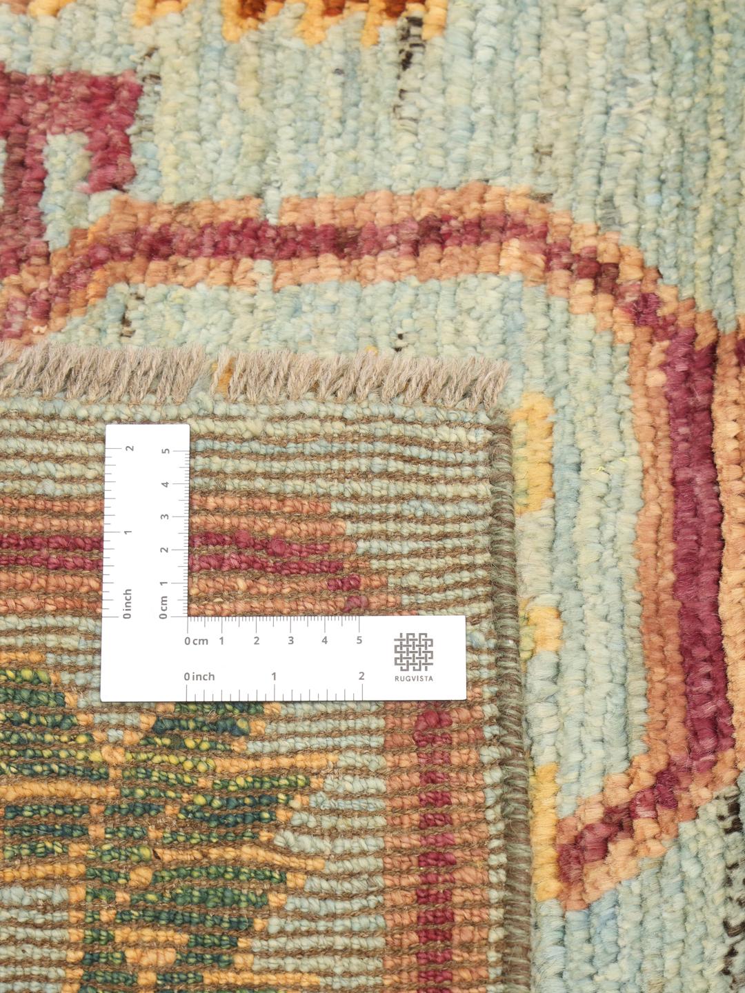 A hand-knotted Afghan runner with a vibrant geometric pattern on a light blue background.