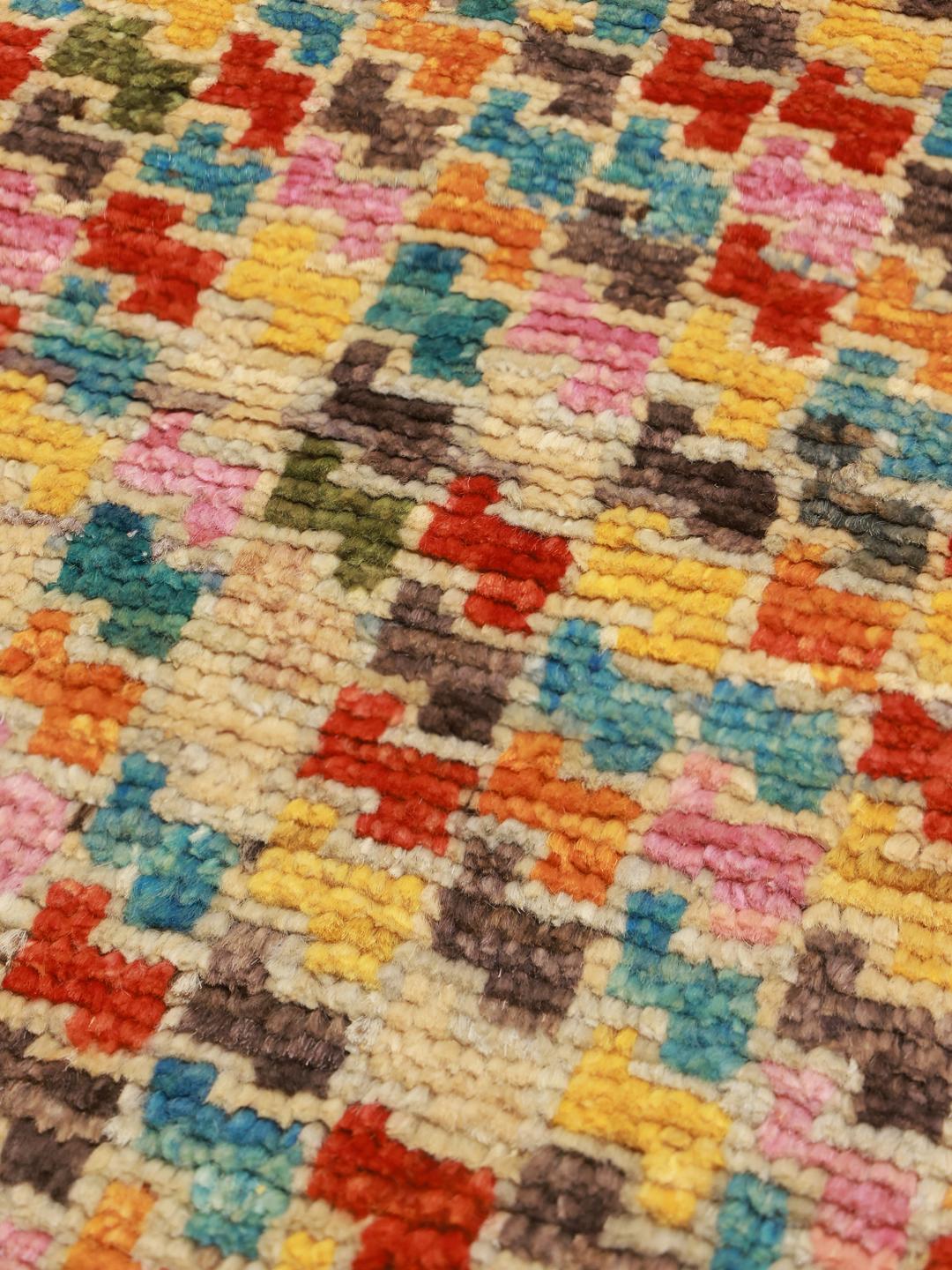 Et levende og farverigt håndknyttet tæppe fra Afghanistan med geometriske mønstre.