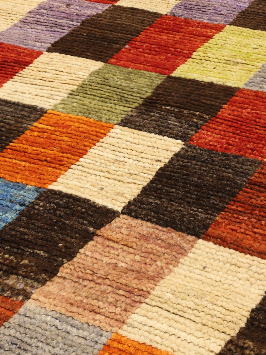 Een rechthoekig, handgemaakt Berber-tapijt uit Afghanistan met een kleurrijk geometrisch blokpatroon.