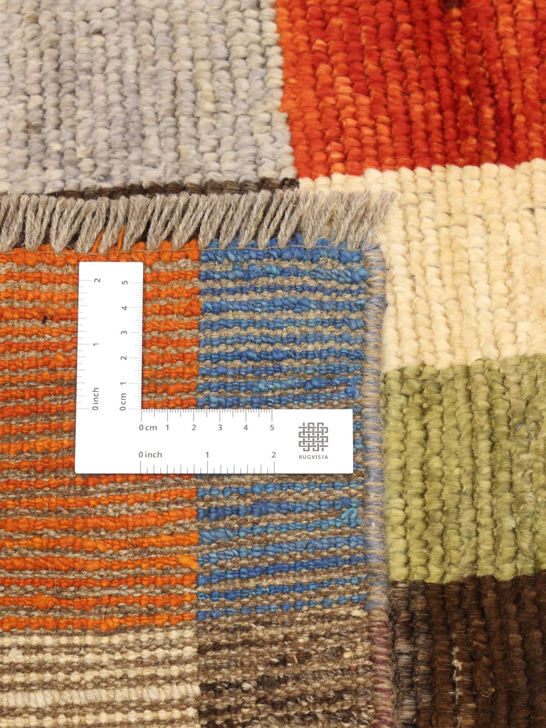 Een rechthoekig, handgemaakt Berber-tapijt uit Afghanistan met een kleurrijk geometrisch blokpatroon.