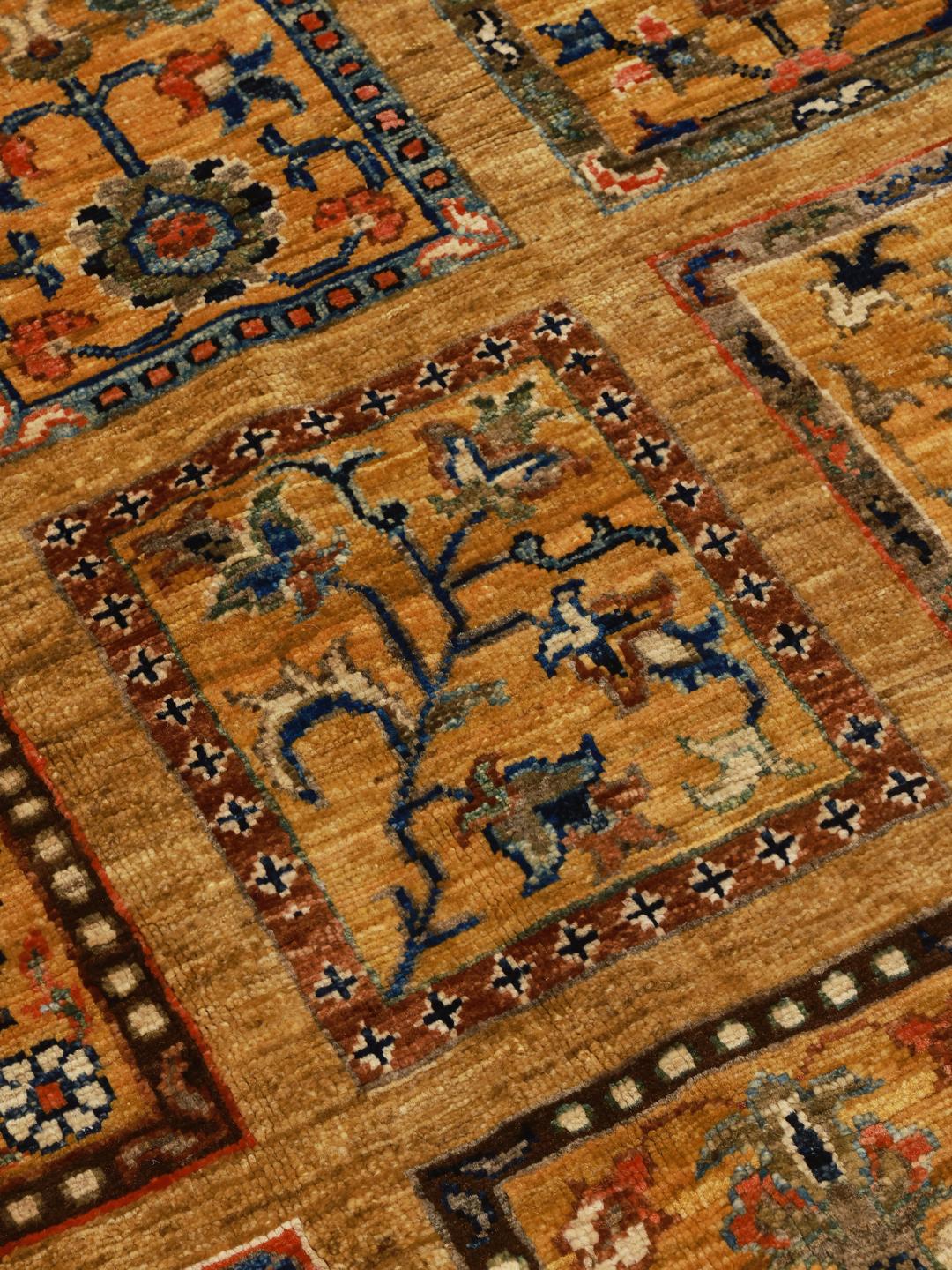 Handgeknoopt Afghaans tapijt met een goudkleurig veld en geometrische rastermotieven in blauw en oranje.