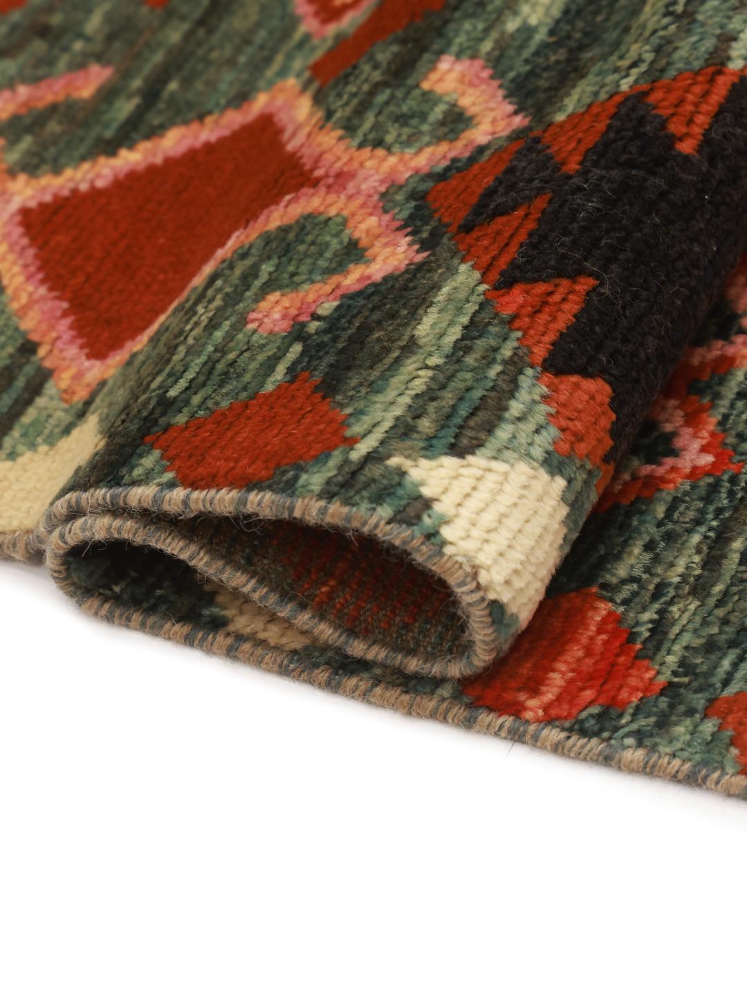 Een rechthoekig Berber Colourful tapijt uit Afghanistan met een donkergroene achtergrond en geometrische patronen.