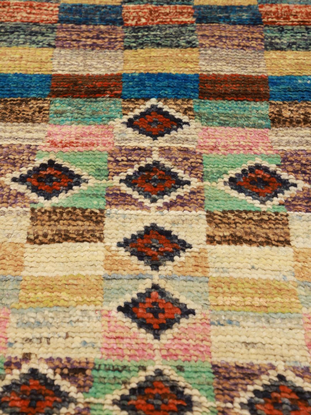 Et farverigt, håndknyttet Berber-tæppe fra Afghanistan med geometriske motiver og et ternet mønster.