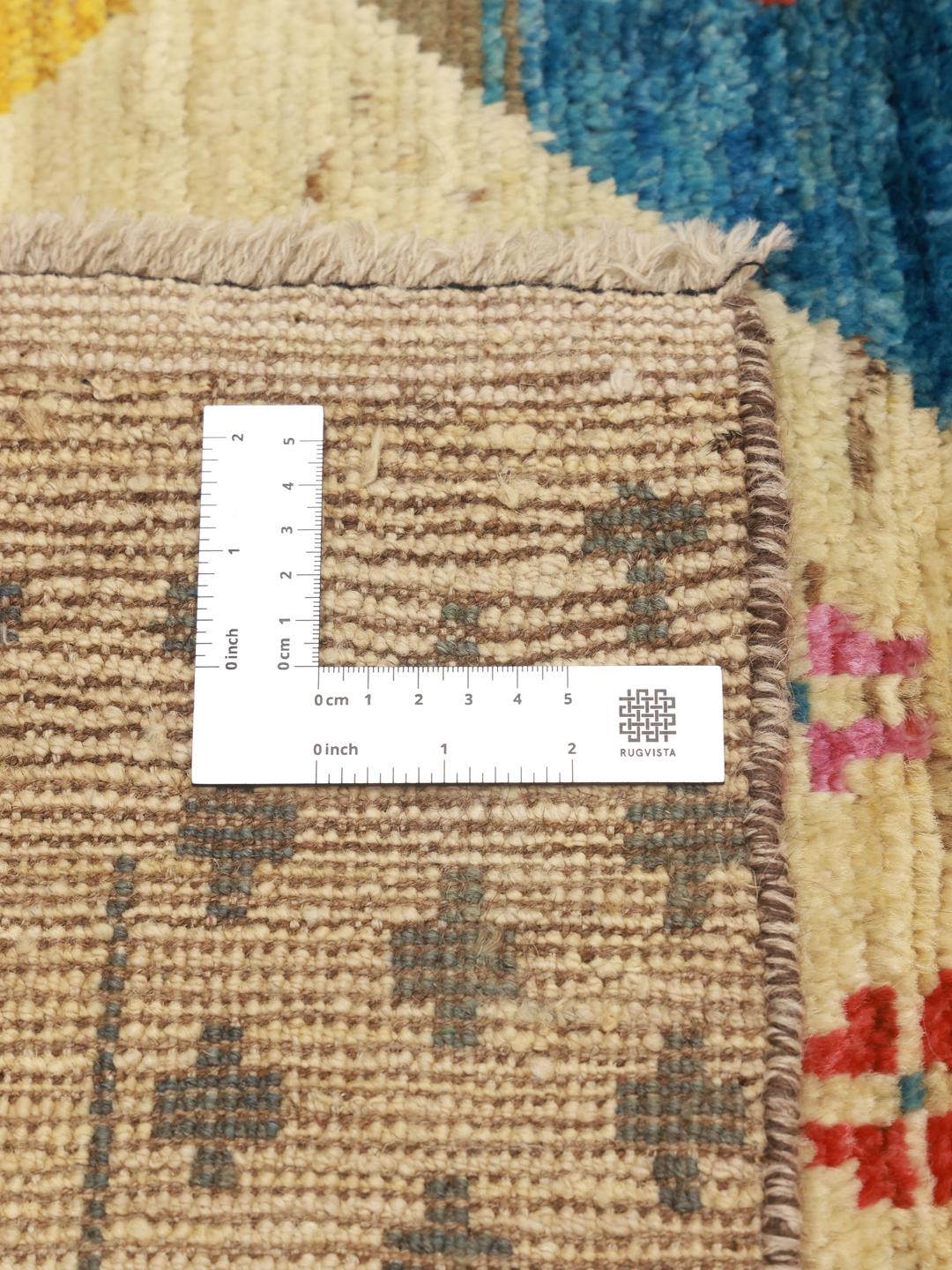 Håndknyttet afghansk tæppe med farverige geometriske diamant- og krydsmotiver på en beige baggrund.