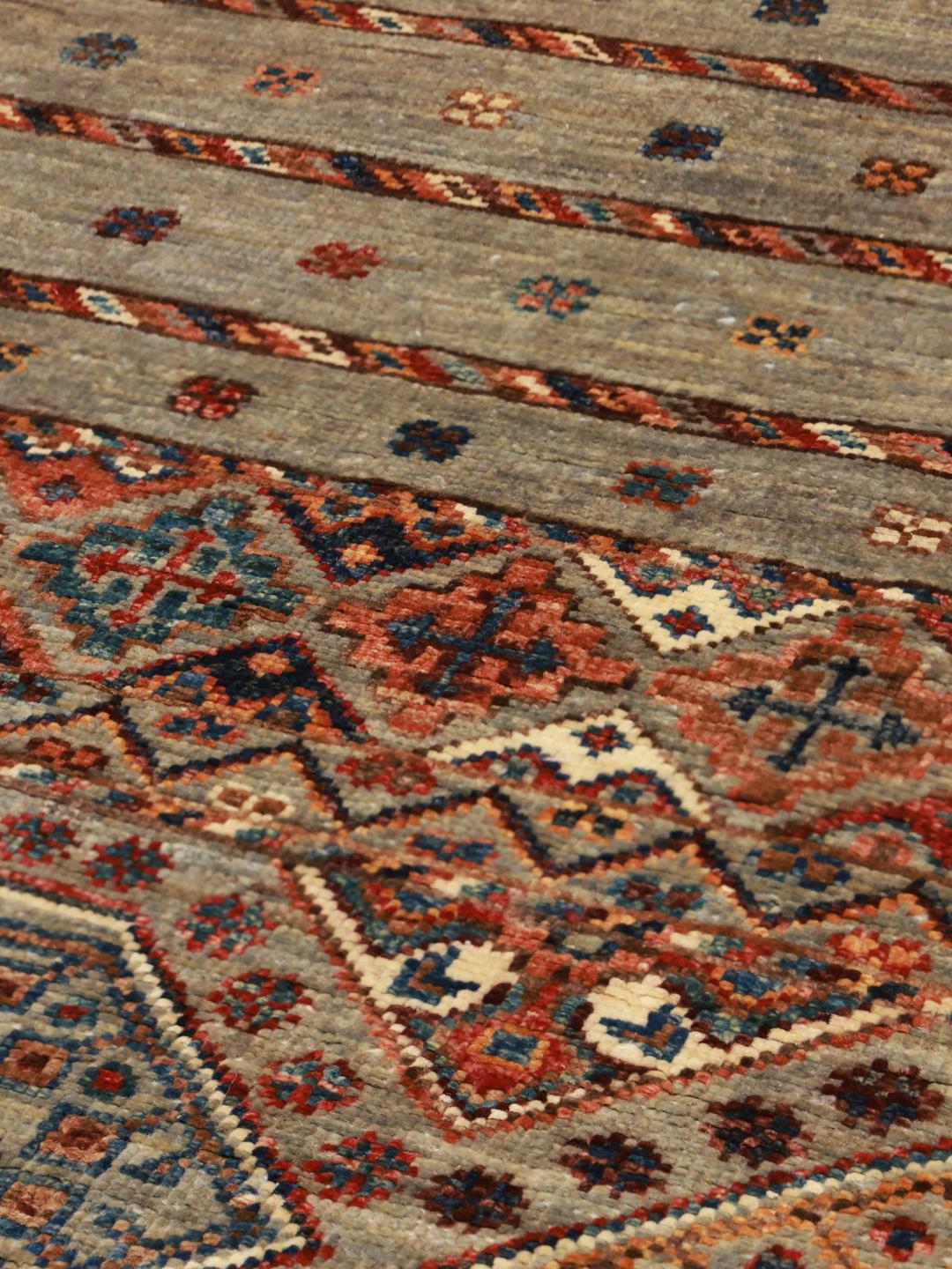 Handgeknoopt Afghaans tapijt met geometrische patronen in blauwe en rode tinten.