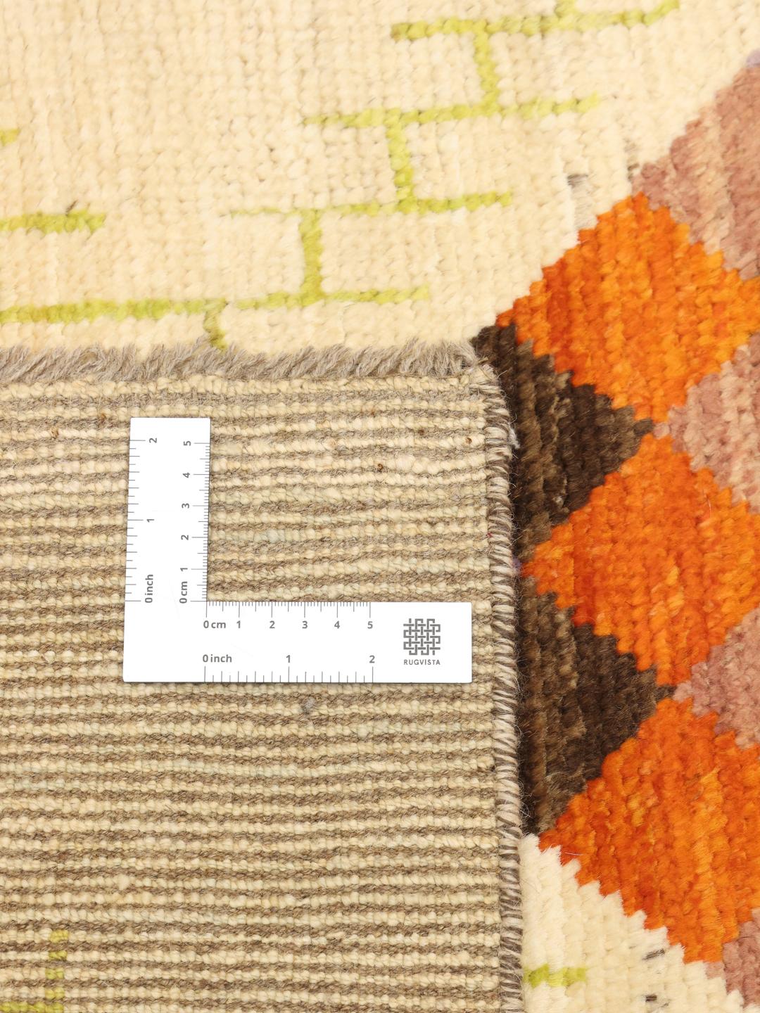 Hand-knotted Afghan rug with colourful geometric diamonds on a beige background.