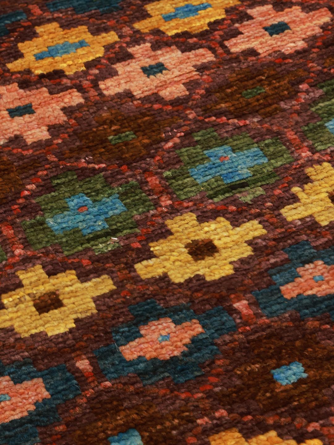 A vibrant, hand-knotted Berber rug from Afghanistan with a geometric multicolored design.