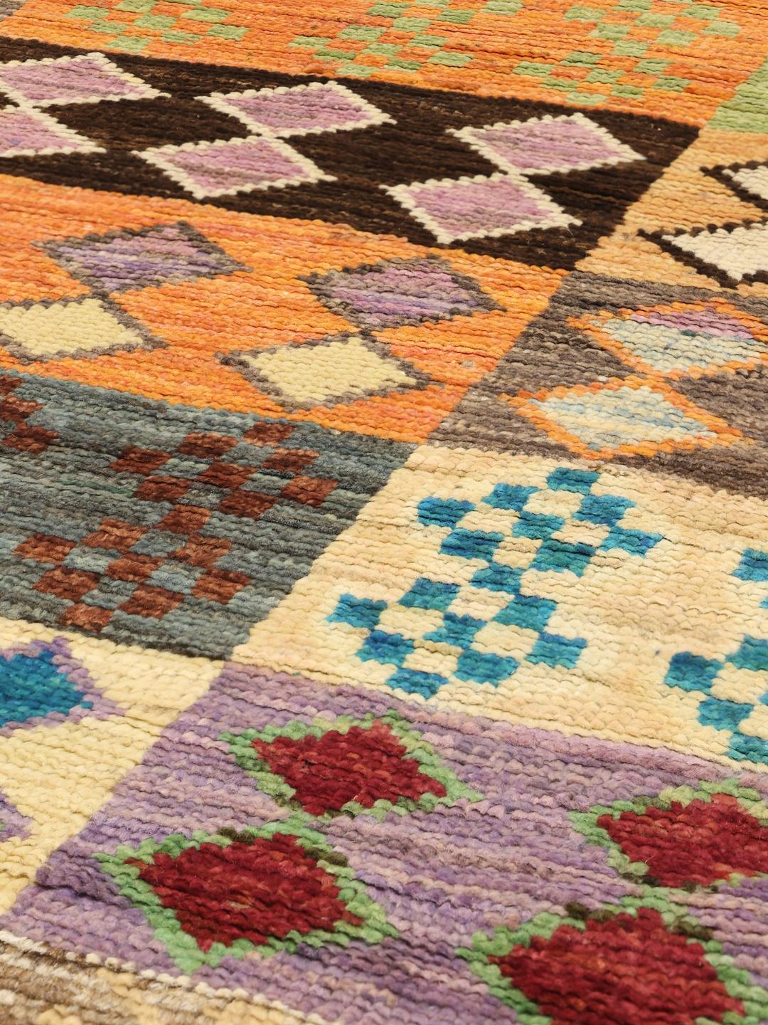 Håndknyttet afghansk tæppe med et flerfarvet patchwork af geometriske motiver og stammemotiver.