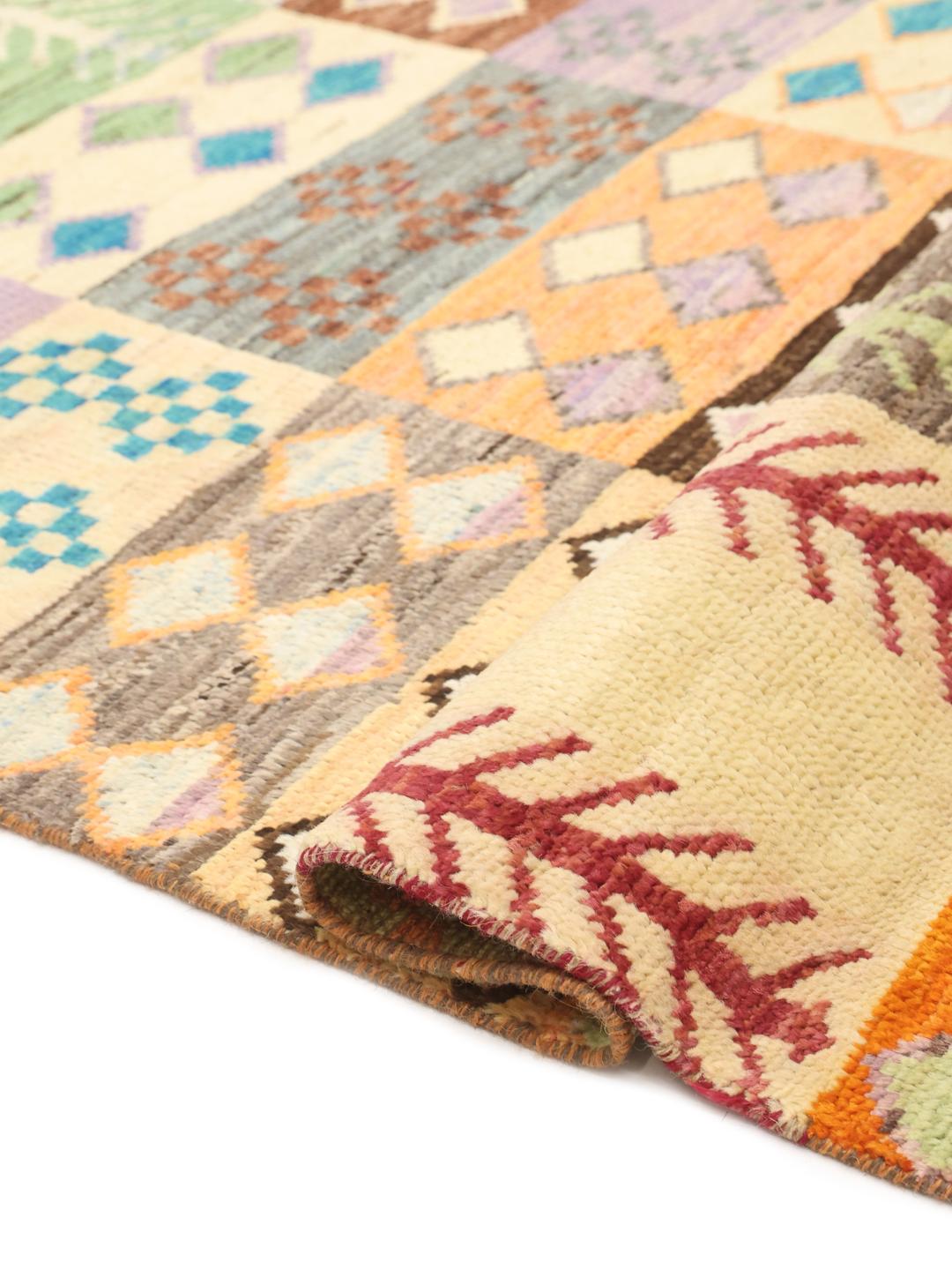 Håndknyttet afghansk tæppe med et flerfarvet patchwork af geometriske motiver og stammemotiver.