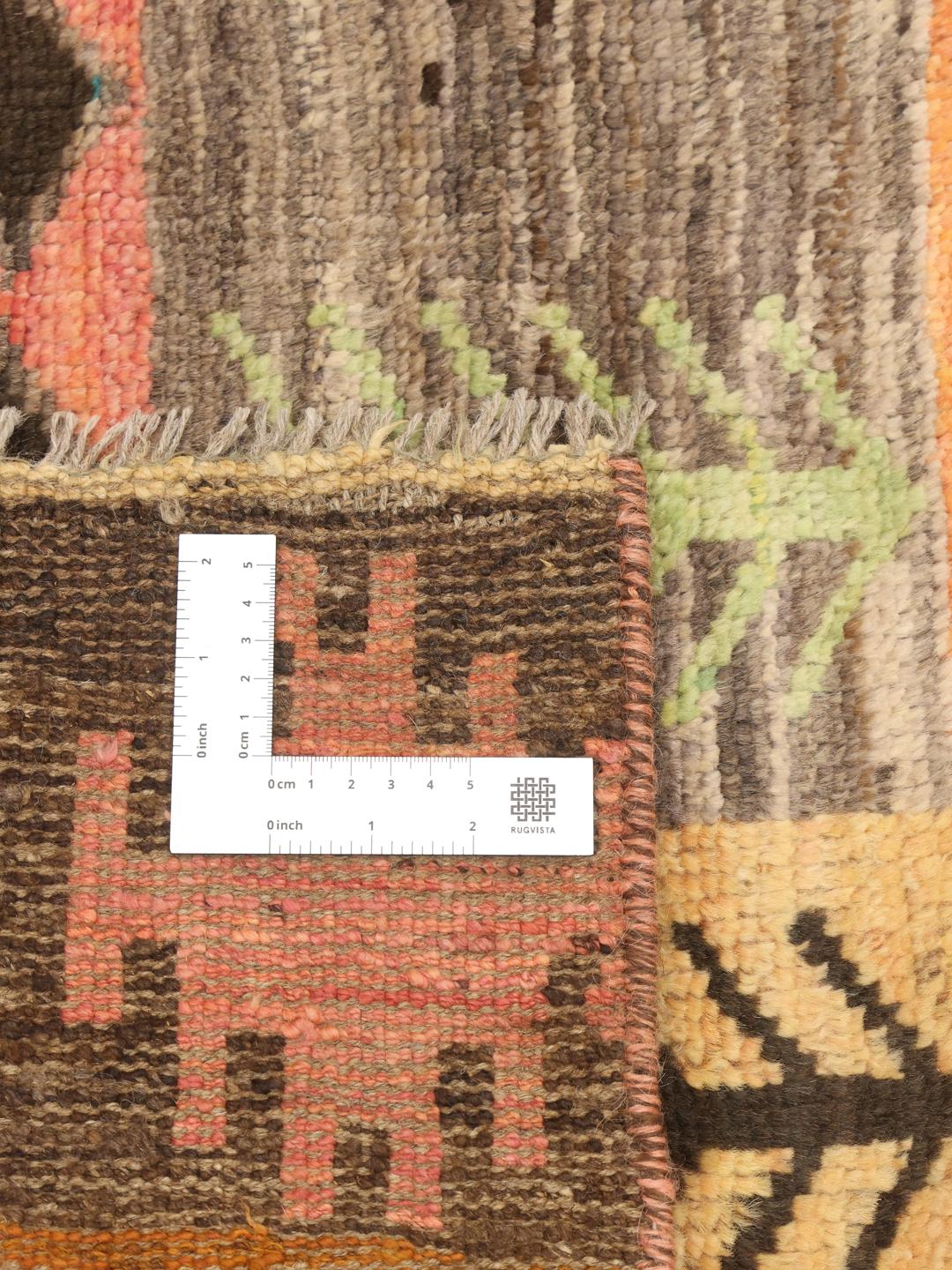 Håndknyttet afghansk tæppe med et flerfarvet patchwork af geometriske motiver og stammemotiver.