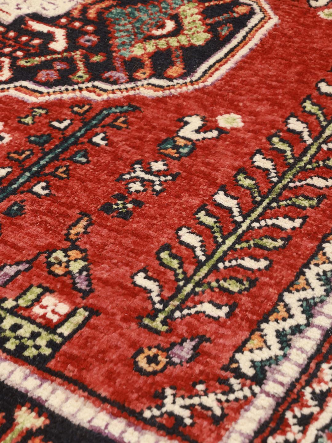 Hand-knotted Kazak rug from Afghanistan featuring red and black geometric patterns.