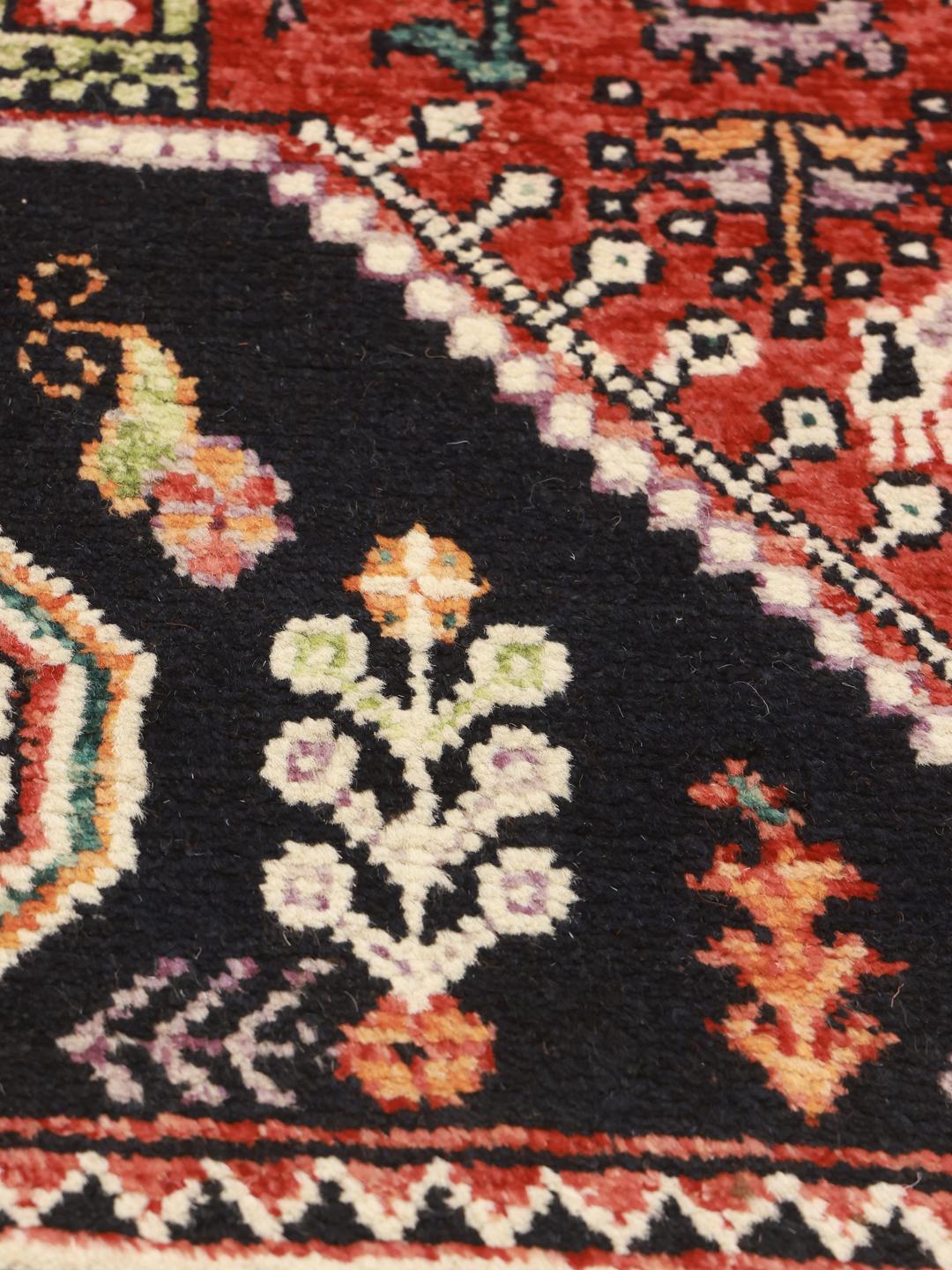 Hand-knotted Kazak rug from Afghanistan featuring red and black geometric patterns.