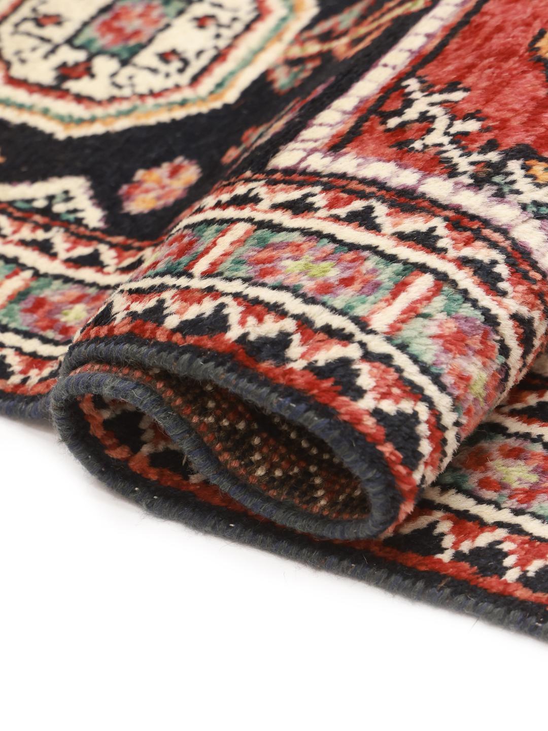 Hand-knotted Kazak rug from Afghanistan featuring red and black geometric patterns.