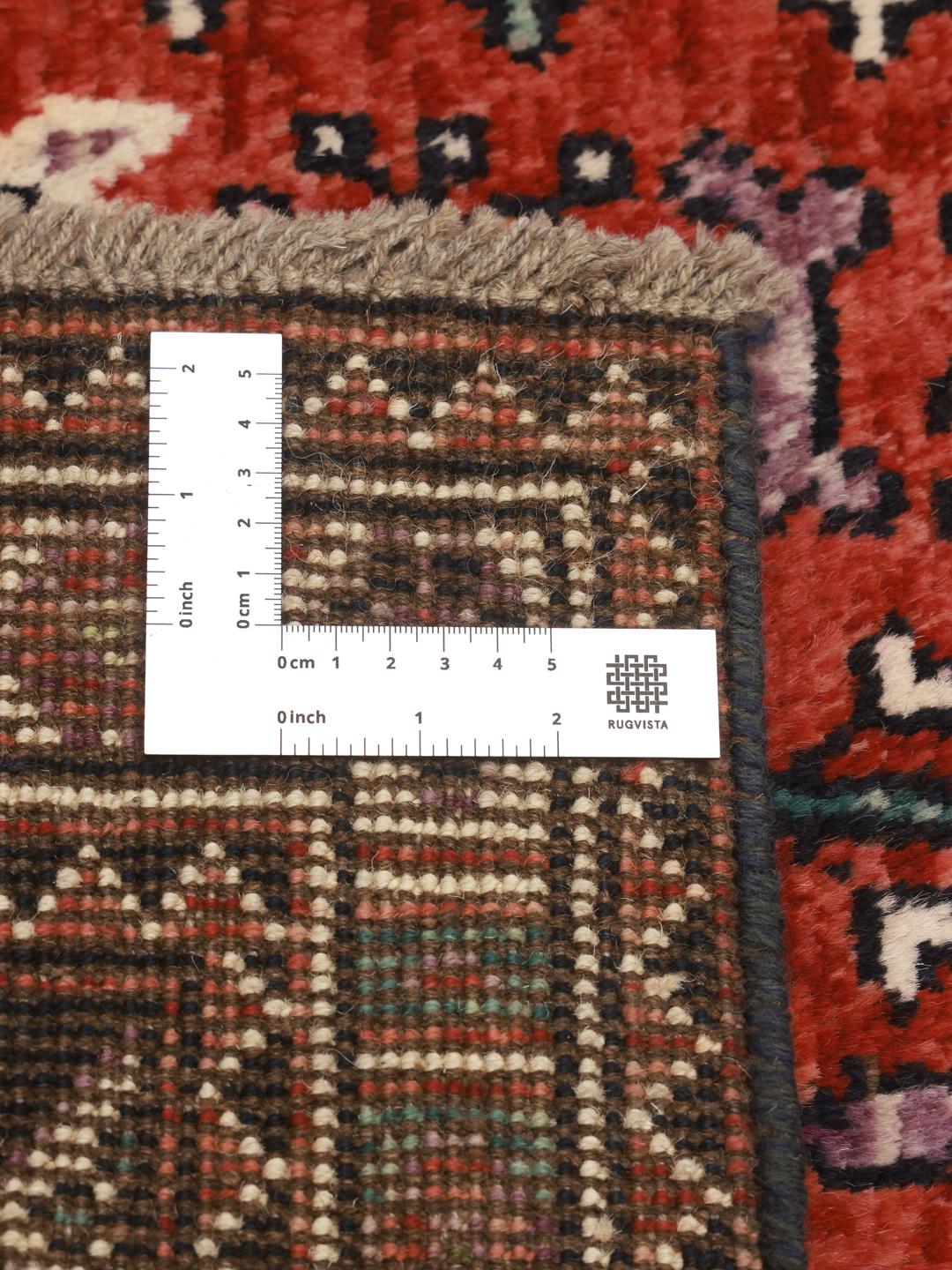 Hand-knotted Kazak rug from Afghanistan featuring red and black geometric patterns.