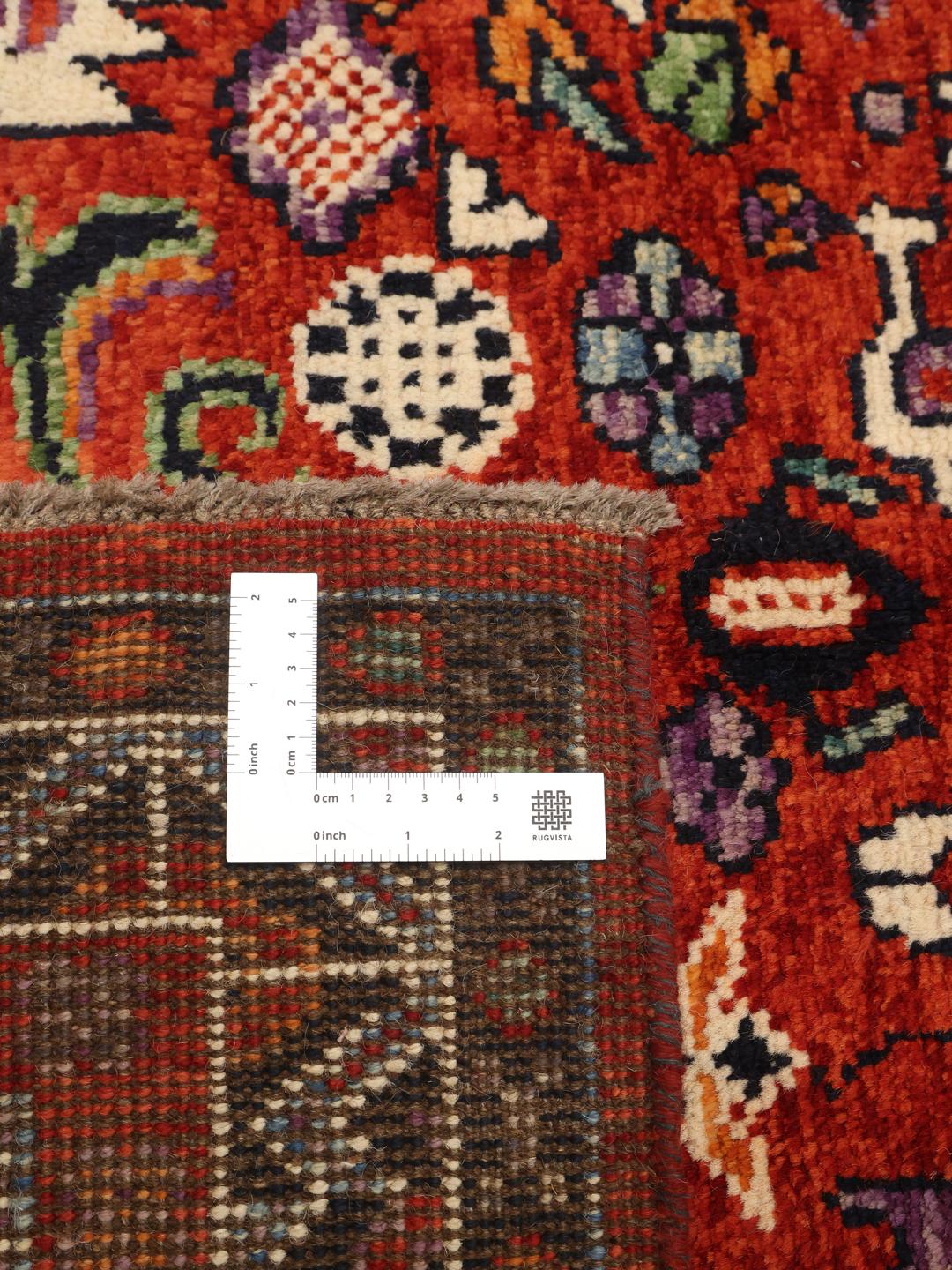 Hand-knotted Kazak rug from Afghanistan featuring a deep red and blue geometric design.