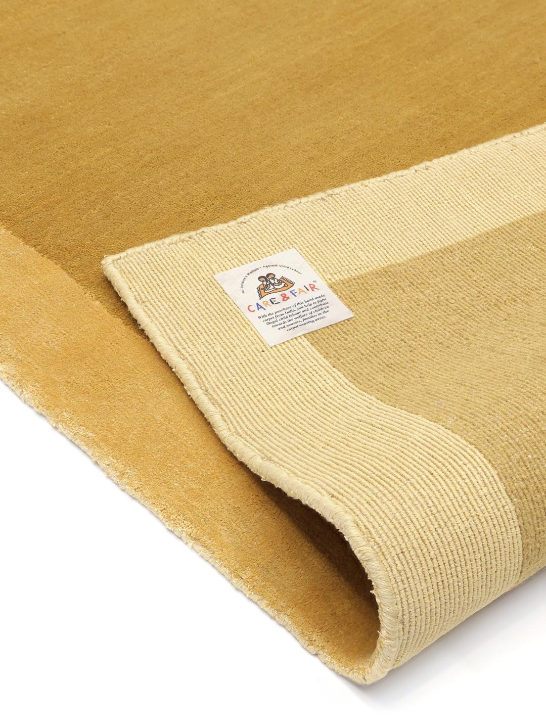 Mosterdgeel wollen tapijt met een decoratieve rand