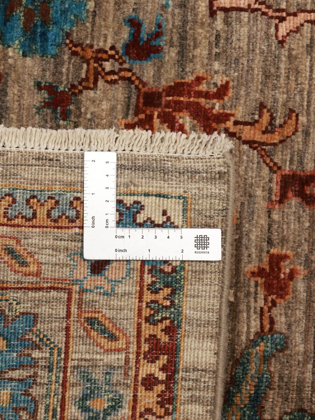 Et håndknyttet afghansk tæppe med blomstermotiver i beige, blå og røde toner.