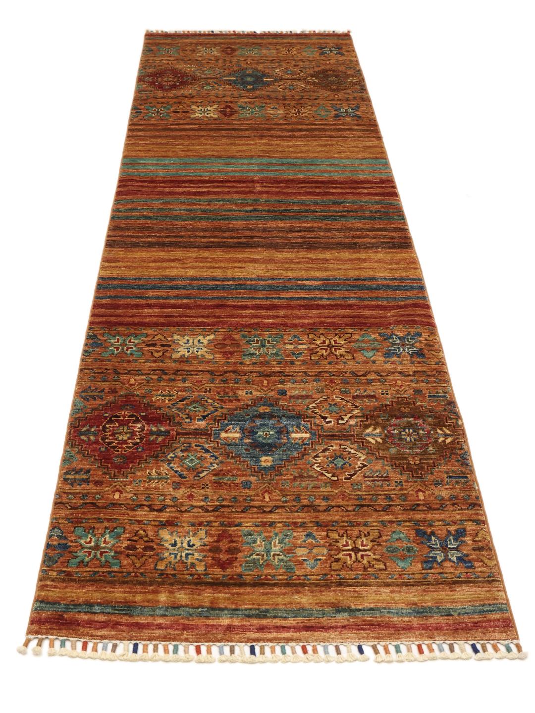 Een lange, handgeknoopte loper uit het Midden-Oosten met tribale geometrische motieven in rode, blauwe en bruine tinten.