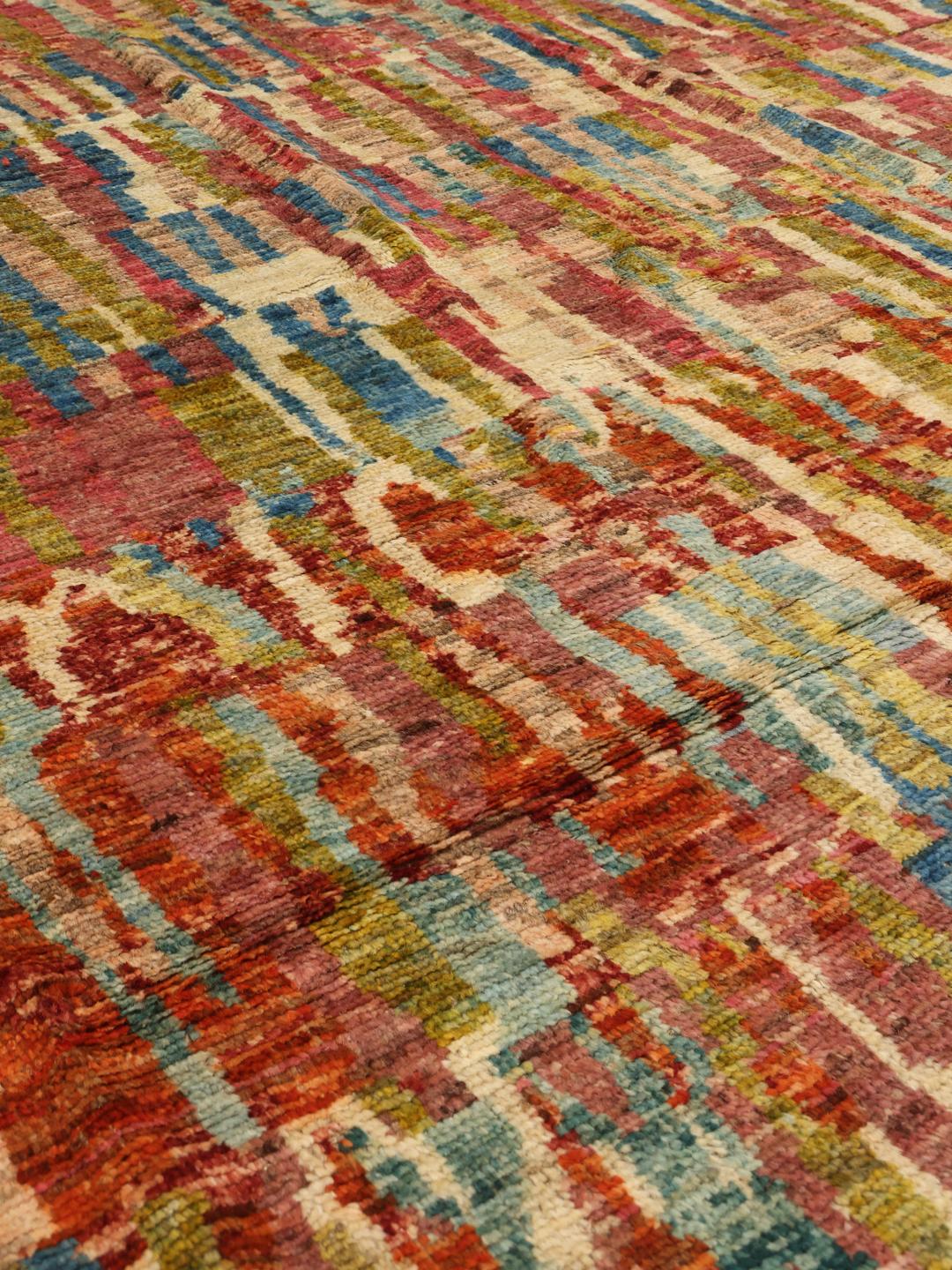 A large, hand-knotted Afghan rug featuring a vibrant, multicolored abstract pattern.